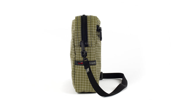 A side view of the Everyday Cubelet in Taiga Halcyon (olive green with a white grid) showing the o-ring attachment point and included 5/8" strap.